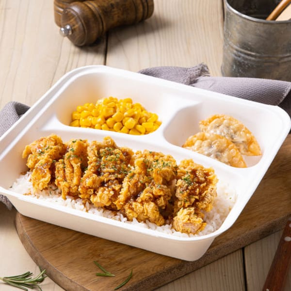Vons Chicken Waimalu fried chicken rice plate with corn and dumplings on a wooden table.